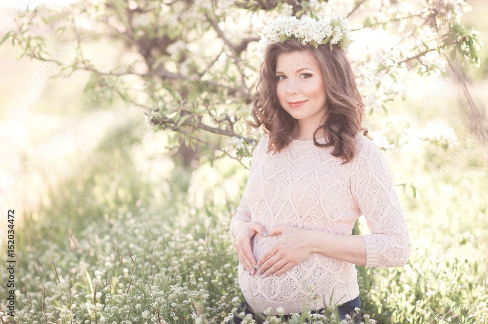 Smiling pregnant woman making heart with fingers in meadow. Looking at camera. Motherhood. Maternity. 20s. Smiling pregnant woman making heart with fingers in meadow. Looking at camera. Motherhood. Maternity. 20s.