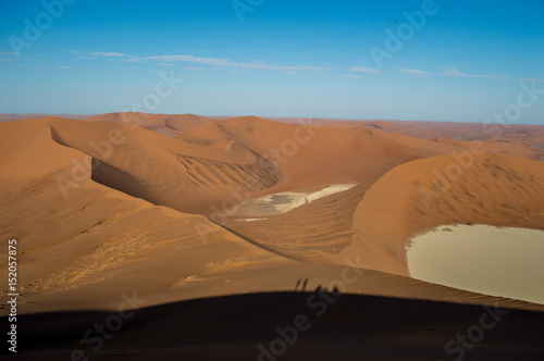 Fototapeta Naklejka Na Ścianę i Meble -  Climbing Big Daddy Dune, Desert Landscape with People Shadows, Looking onto Sossusvlei Salt Pan, Namibia
