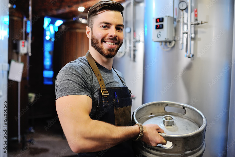 Male brewer with a metal beer barrel Male brewer with a metal beer barrel