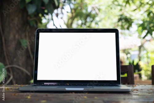 Mockup image of laptop with blank white screen on vintage wooden table in nature outdoor park