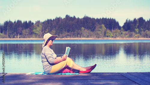 ältere Frau beim Lesen am See