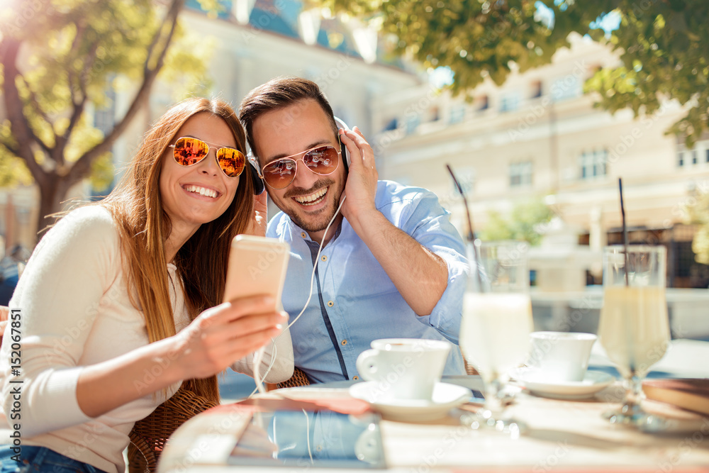 Dating. Young couple drinking coffee and having fun with mobile phone in the cafe. Love, dating, technology, lifestyle Dating. Young couple drinking coffee and having fun with mobile phone in the cafe. Love, dating, technology, lifestyle