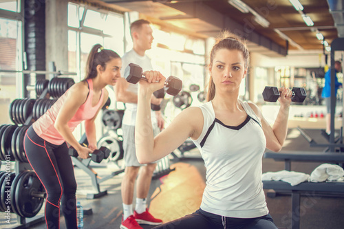 Young woman lifting dumbbells at the gym.
