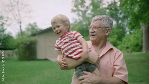Grandfather carrying grandson on his hands in nature in summer 4k
