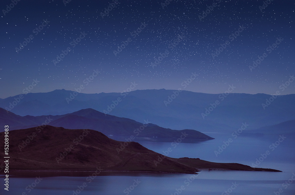 Fototapeta premium Hills and mountains are reflected in the lake at night.