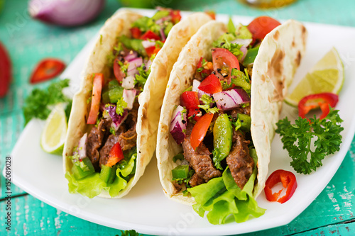 Mexican tacos with beef in tomato sauce and salsa