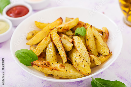 Ruddy Baked potato wedges with herbs on a light background.