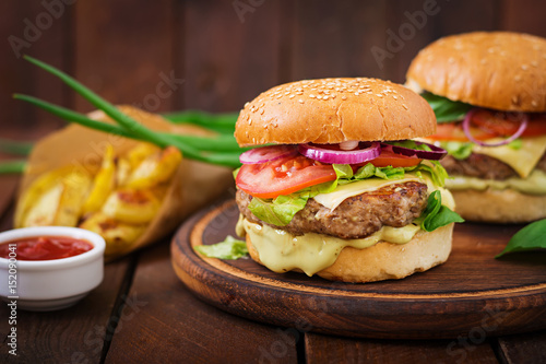 Big sandwich - hamburger with juicy beef burger  cheese  tomato   and red onion on wooden background