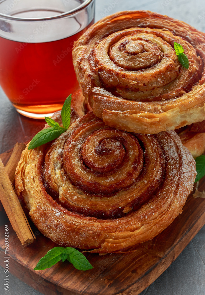 Fototapeta premium Freshly Baked Traditional Sweet Cinnamon Rolls, Swirl with hot black Tea and mint