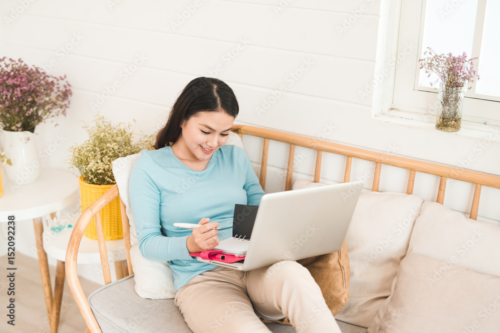 Happy young asian entrepreneur working with a laptop at home. Happy young asian entrepreneur working with a laptop at home.
