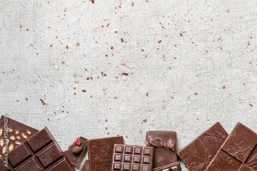 Variety of bars of raw homemade chocolate on cloth background. Vegetarian concept of healthy food. Top view. Copy space