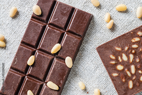 Bars of raw vegan handmade chocolate with pine seeds on cloth background. Vegetarian concept of healthy food. Top view