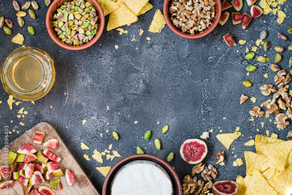 Ingredients layout for baking soft cheese brie with figs, walnuts, pistachios and honey. Snack concept with chips. Top view on dark background with copy space Ingredients layout for baking soft cheese brie with figs, walnuts, pistachios and honey. Snack concept with chips. Top view on dark background with copy space