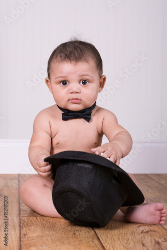 Adorable baby boy sitting on the floor wearing a bow tie