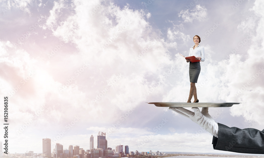 Attractive businesswoman on metal tray with red book in hands against cityscape background Attractive businesswoman on metal tray with red book in hands against cityscape background