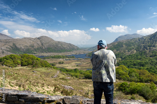 Male tourist, rear view taking pictures of Killarney National Park on the Ring of Kerry, County Kerry, Ireland. Beautiful scenic natural irish countryside landscape.