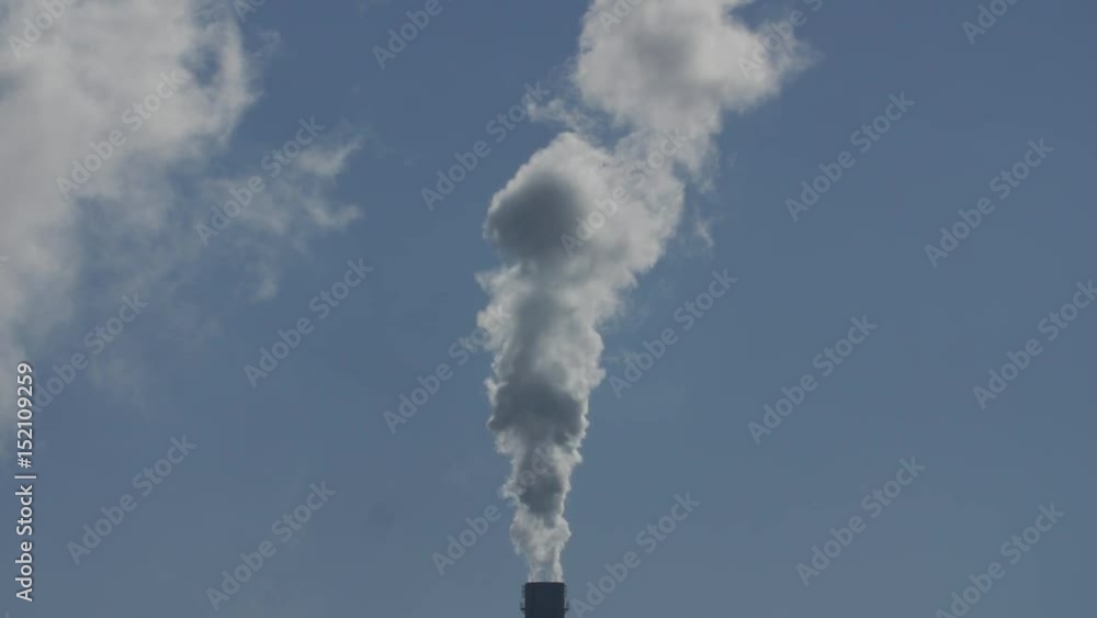 Air pollution by smoke coming out of the factory chimneys in the industrial zone. Blue sky, slow motion. Air pollution by smoke coming out of the factory chimneys in the industrial zone. Blue sky, slow motion.