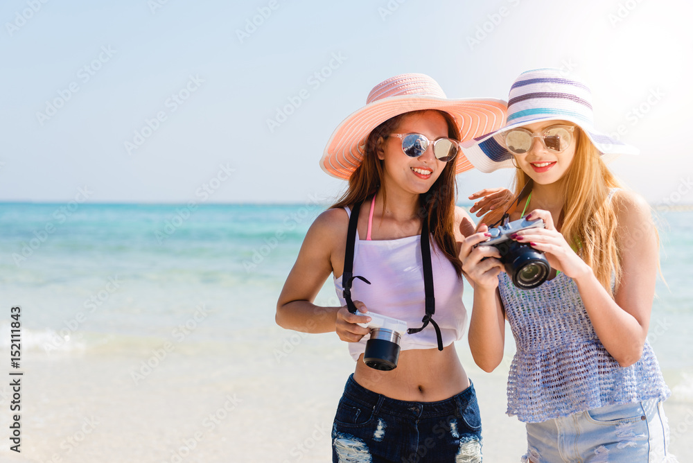 Two cool trendy hipster girls at the beach enjoying vacation on a tropical island, perfect tanned body, healthy skin, sexy stylish casual wear, bikini, blonde and brunette with the camera, sunglasses Two cool trendy hipster girls at the beach enjoying vacation on a tropical island, perfect tanned body, healthy skin, sexy stylish casual wear, bikini, blonde and brunette with the camera, sunglasses