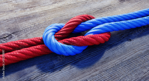 Kreuzknoten mit rotem und blauem Seil auf Holz