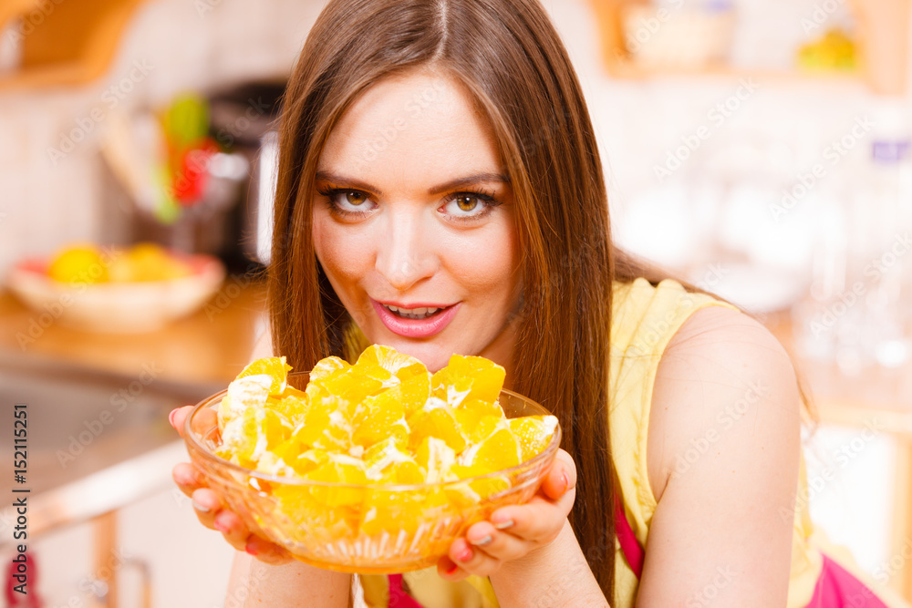 Woman holds bowl full of sliced orange fruits