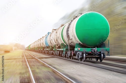 Freight train passing oil-loading, fuel oil, fuel tanks in motion.