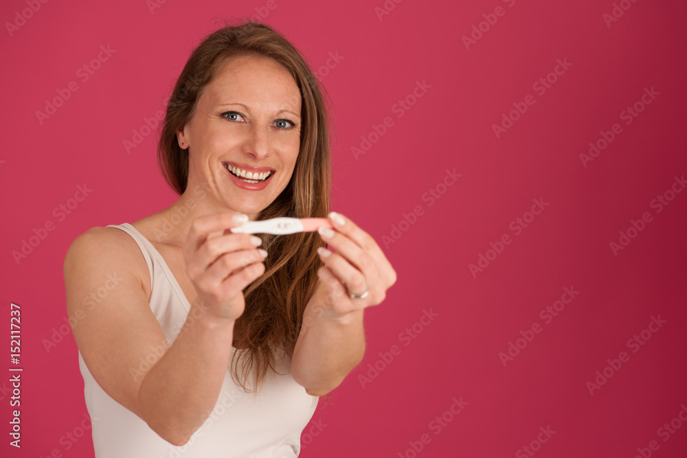 Happy woman with pregnancy test isolated over pink background Happy woman with pregnancy test isolated over pink background