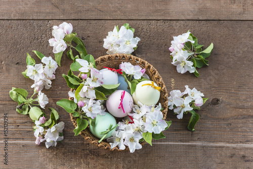 easter concept/basket with easter eggs and apple flowers on wooden background