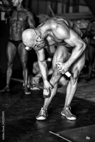 Bodybuilding competition backstage: contestant being oiled and fake tan applied to skin. black and white photography.