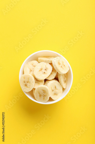 Sweet bananas in bowl on yellow background