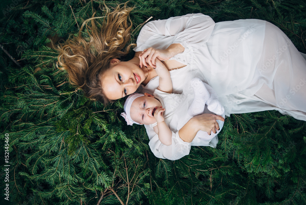 Mom and daughter are lying on Christmas trees Mom and daughter are lying on Christmas trees