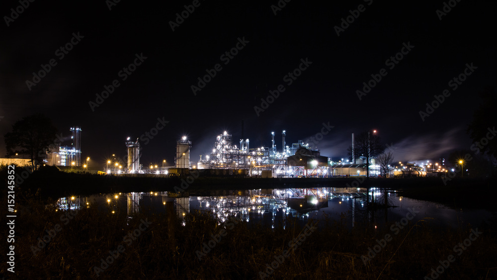 Lights of petrochemical refinery at night reflecting in water. Tessenderlo, Belgium