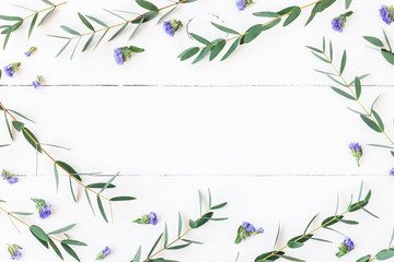 Flowers composition. Frame made of wildflowers and eucalyptus branches on white background. Flat lay, top view