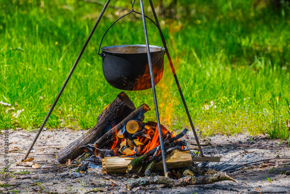 touristic cauldron on a tripod in a fire touristic cauldron on a tripod in a fire
