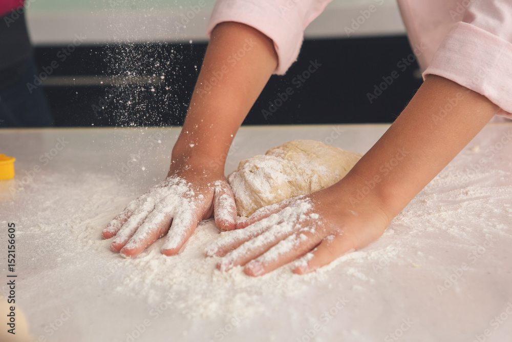 Young mother and daughter cooking dough together