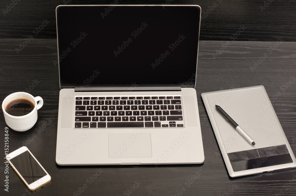 Open notebook, graphics tablet, coffee cup and phone on a black table Open notebook, graphics tablet, coffee cup and phone on a black table