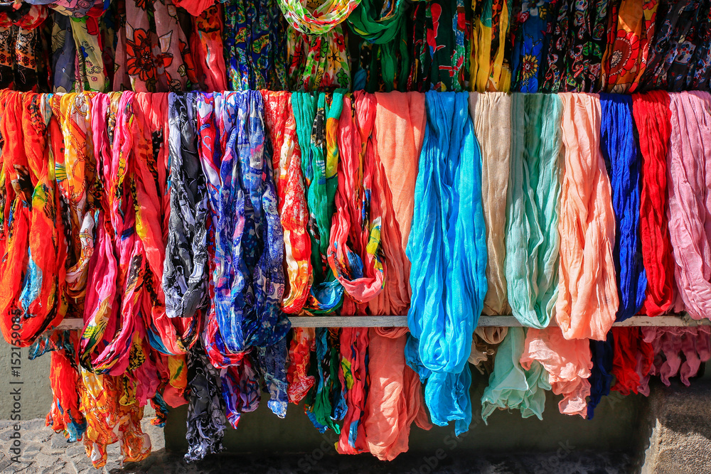 Many colorful scarves hanging at market