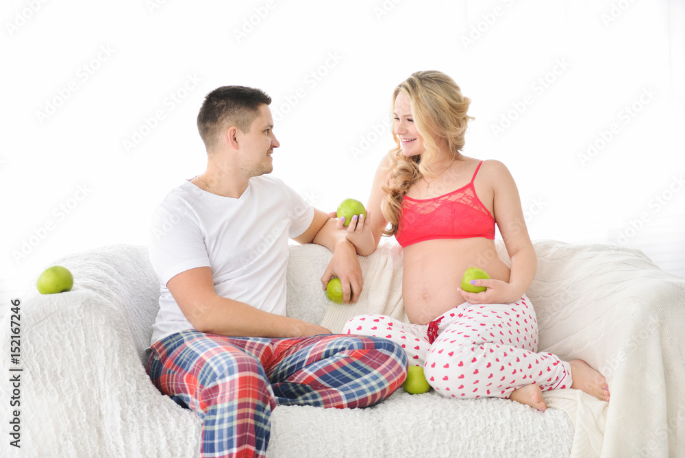 pregnant woman eating an apple and looking at her husband pregnant woman eating an apple and looking at her husband