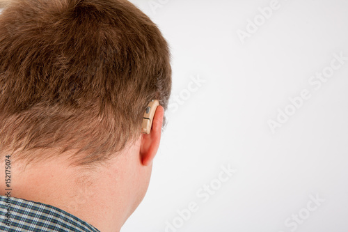 Close up of a man’s ear wearing hearing aid viewed from back.