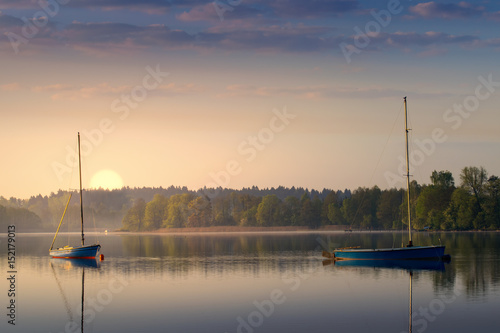 Fototapeta Naklejka Na Ścianę i Meble -  Yachts float on the calm waters of the lake. Early morning. Masuria, Poland .