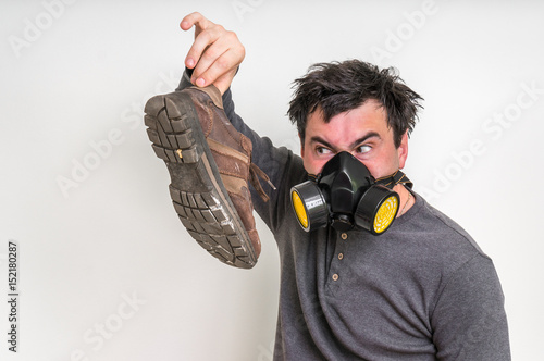 Man with gas mask is holding dirty stinky shoe