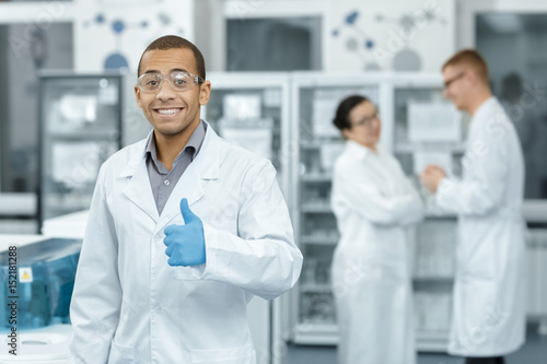 Professional chemist posing cheerfully at the lab showing thumbs up