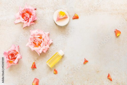 Spa setting with flowers, rose moisturizing cream and essential oil. Spa theme. Top view, blank space, concrete background