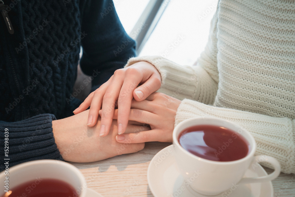 Female palms lie on the men next to two cups of tea Female palms lie on the men next to two cups of tea