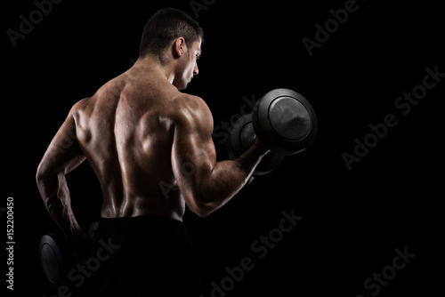 Athletic man training biceps on black background