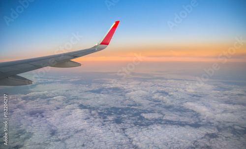 Plane wing on the sky with sunset and cloud, aerial view from airplane window.