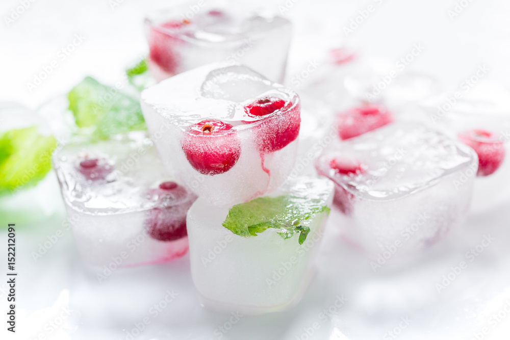Ice cubes with berries and mint for summer drink on white background Ice cubes with berries and mint for summer drink on white background