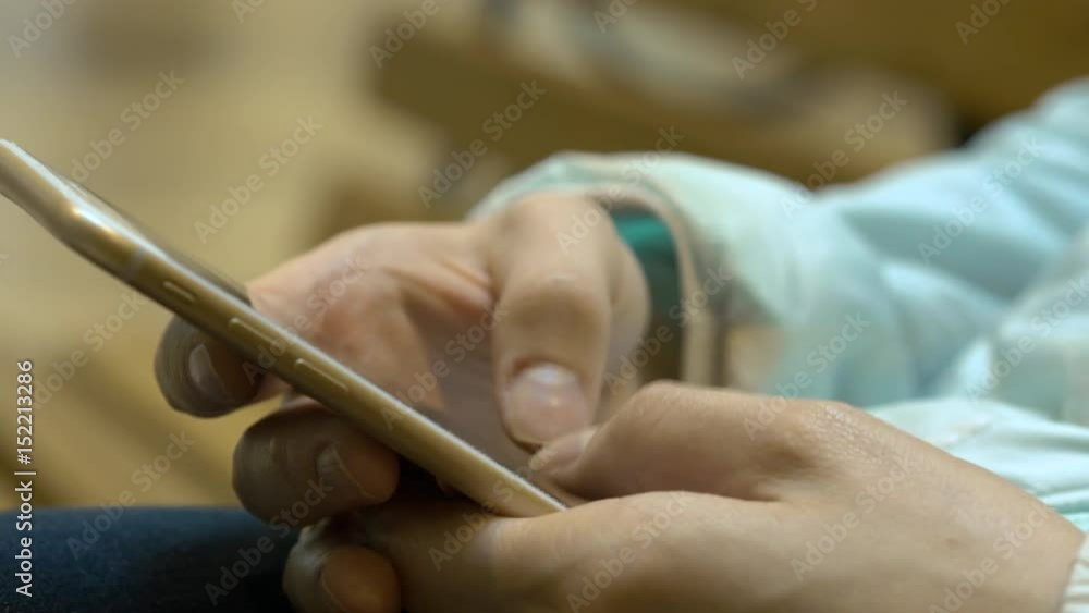 Girl Hand Holding Mobile Phone While Sitting On The Bench At The Mall Girl Hand Holding Mobile Phone While Sitting On The Bench At The Mall