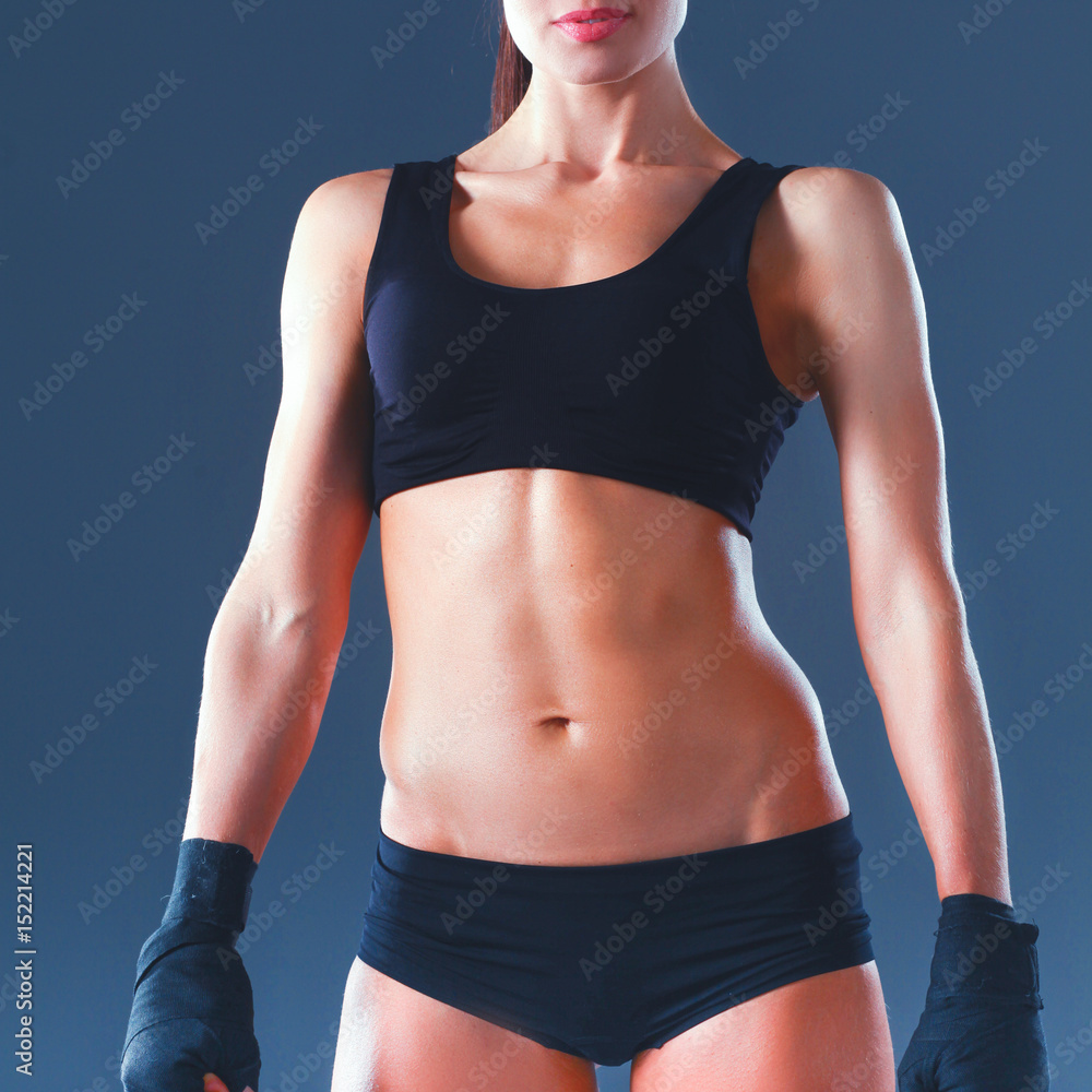 Muscular young woman standing on gray background. Muscular young woman standing on gray background.