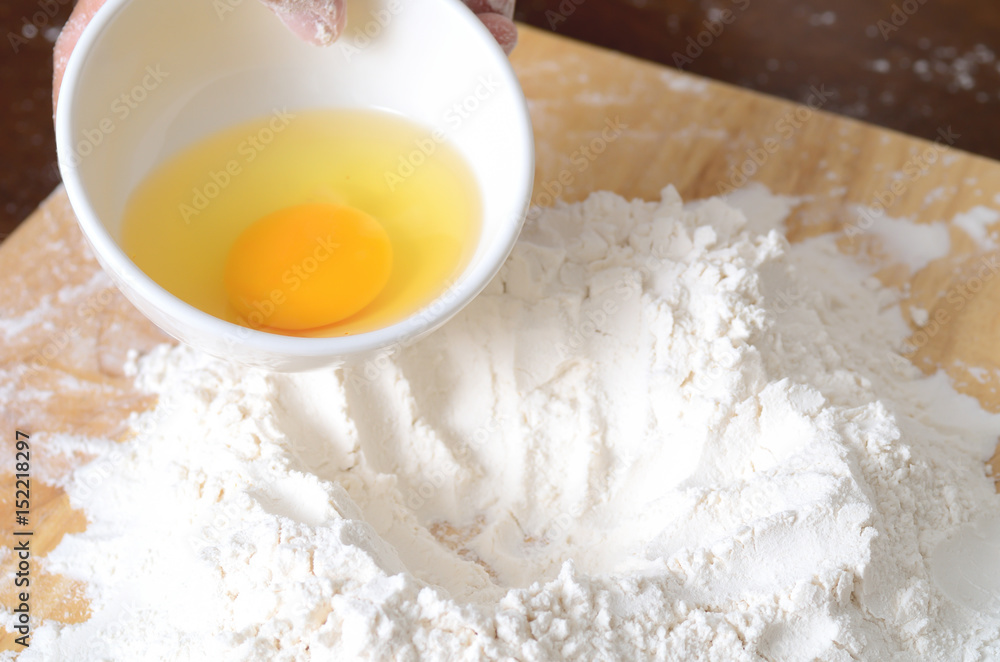 Pouring egg yolk mixing with flour to making bread or cake,bakery cooking Pouring egg yolk mixing with flour to making bread or cake,bakery cooking