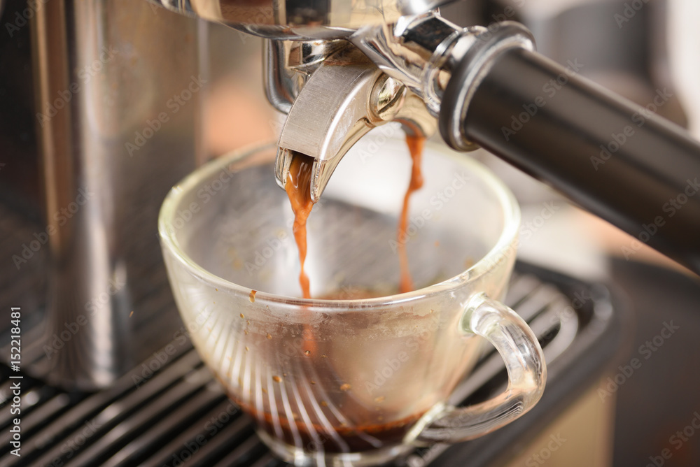 Coffee flowing into a cup from espresso machine Coffee flowing into a cup from espresso machine